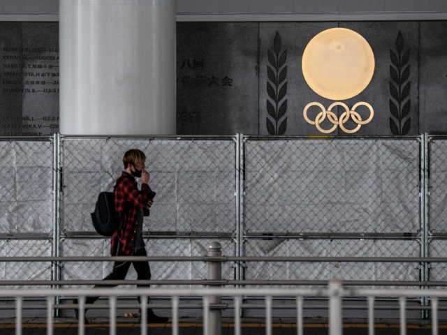 TOKYO, JAPAN - OCTOBER 13: A man walks past Olympic Rings and historic track records engra