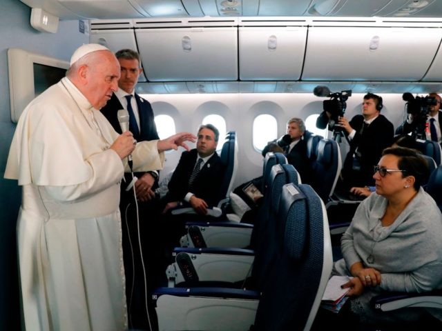 Pope Francis (L) speaks to reporters during a news conference onboard the papal plane on h