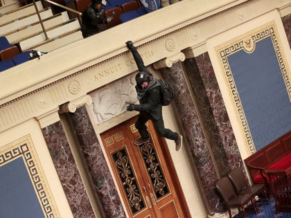 WASHINGTON, DC - JANUARY 06: A protester is seen hanging from the balcony in the Senate Chamber on January 06, 2021 in Washington, DC. Congress held a joint session today to ratify President-elect Joe Biden's 306-232 Electoral College win over President Donald Trump. Pro-Trump protesters have entered the U.S. Capitol …