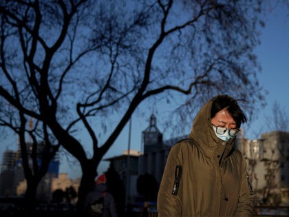 A woman wearing a face mask to help curb the spread of the coronavirus walks on a street as the capital city is hit by cold wind in Beijing, Wednesday, Jan. 6, 2021. (AP Photo/Andy Wong)