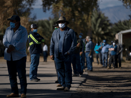 Hispanic farm workers wait in line to receive the Pfizer-BioNTech COVID-19 vaccine in Mecc