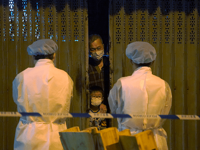 Government workers wearing personal protective equipment, stand guard as residents are str