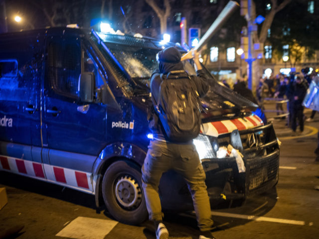 A demonstrator hits a police van with a bat during clashes following a protest condemning