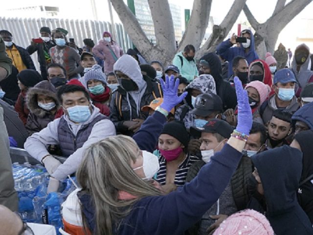A woman handing out food and water speaks to asylum seekers waiting in Mexico, Friday, Feb. 19, 2021, in Tijuana, Mexico. After waiting months and sometimes years in Mexico, people seeking asylum in the United States are being allowed into the country starting Friday as they wait for courts to …