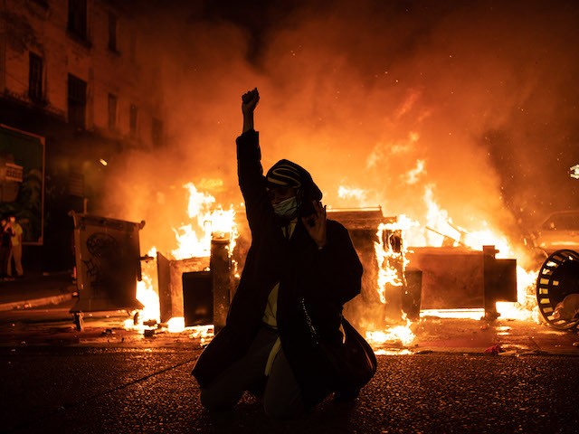In this June 2020 photo, a rioter raises their fist as a fire burns in the street after clashes with law enforcement near the Seattle Police Departments East Precinct shortly after midnight. (David Ryder/Getty Images)
