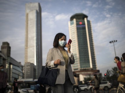 A women wears a mask while uses iPhone pass the crossroads on May 11, 2020 in Wuhan, China