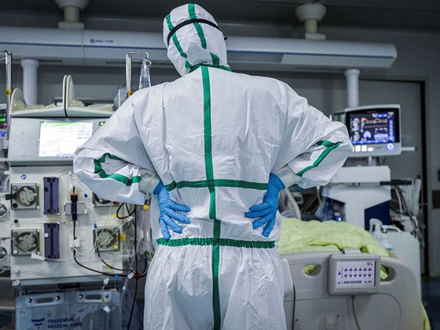 This photo taken on February 24, 2020 shows a doctor looking at a patient infected by the COVID-19 coronavirus at a hospital in Wuhan in China's central Hubei province. - The new coronavirus has peaked in China but could still grow into a pandemic, the World Health Organization warned, as …