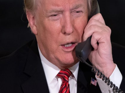 US President Donald Trump speaks on the telephone as he answers calls from people calling into the NORAD Santa tracker phone line in the State Dining Room of the White House in Washington, DC, on December 24, 2018. (Photo by SAUL LOEB / AFP) (Photo credit should read SAUL LOEB/AFP …