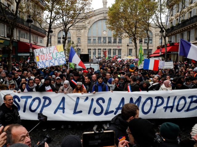 People wave French national flags, chant slogans and hold placards reading messages such as "Stop to all types of racism" (rear L) and "Stop to Islamophobia" (front C) as they take part in a demonstration march in front of the Gare du Nord, in Paris to protest against Islamophobia, on …