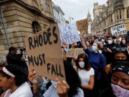 Protestors hold placards during a protest called by the Rhodes Must Fall campaign calling for the removal of the statue of British imperialist Cecil John Rhodes outside Oriel College, at the University of Oxford on June 9, 2020. - Following the toppling of slave trader Edward Colston during a Black …