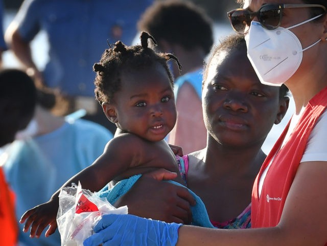 A migrant from Lybia and her child disembark from Italy's Guardia Costiera (Coast Guard) boat in the Italian Pelagie Island of Lampedusa on July 31, 2020. - The reception centre on the island is already overcrowded with migrants who have been arriving daily by the hundreds in recent weeks. (Photo …