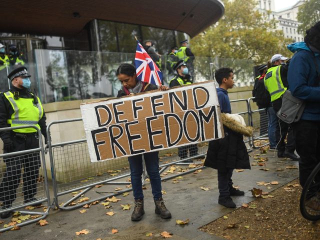 LONDON, ENGLAND - OCTOBER 24: A protester holds a sign reading 'Defend Freedom' during a Unite for Freedom march outside New Scotland Yard on October 24, 2020 in London, England. Hundreds of anti-mask and anti-lockdown protesters marched through central London, England demonstrating against latest Coronavirus lockdown measures. (Photo by Peter …