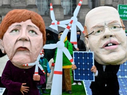 Climate and environmental activists dressed as German Chancellor Angela Merkel and German Economy Minister Peter Altmaier display mockups of tiny windturbines and solarpanels during a demonstration in front of the Reichstag, the building which houses the Bundestag (lower house of parliament), asking for more renewable energy, in Berlin on October …