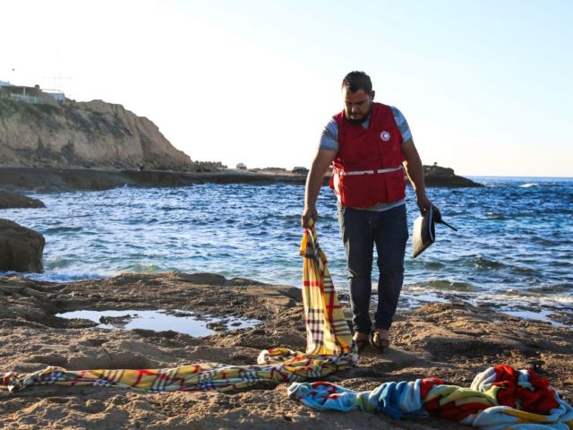 A member of the Libyan Red Crescent checks blankets in which the bodies of drowned migrant children were wrapped on the shore of Zawia, west of the Libyan capital Tripoli, after the corpses were transported to a nearby hospital morgue, on December 16, 2020. - The bodies of four migrant …
