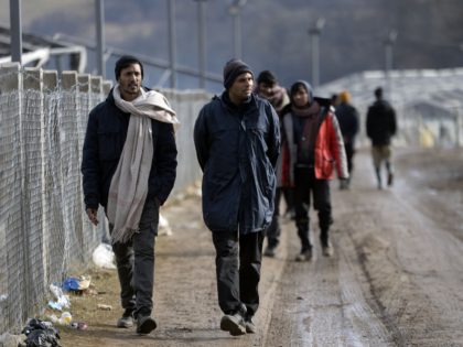 Illegal men walk along fence, at the Lipa camp near the north-western Bosnian town of Biha