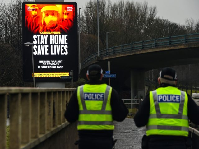 Police officers walk past a Covid-19 information board alongside the Clydeside Expressway in Glasgow on January 20, 2021. (Photo by Andy Buchanan / AFP) (Photo by ANDY BUCHANAN/AFP via Getty Images)