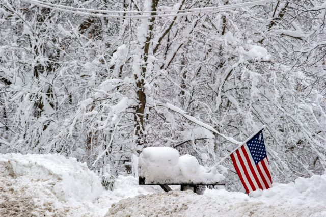 A US Flag stands out in stark contrast to the white snow around a mailbox during winter st
