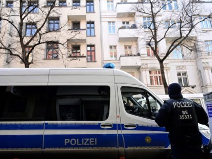 A police officer stands next to a police car parked in front of a building in Berlin's Neukoelln district that was searched earlier during raids against organized clan criminality on February 18, 2021 in the German capital. - Several hundred police officers carried out a large-scale raid in Berlin and …
