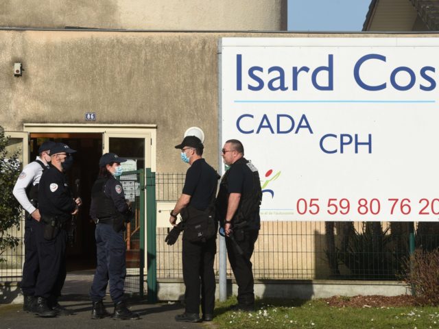Police officers stand at the entrance of the Isard COS Reception Centre for Asylum Seekers