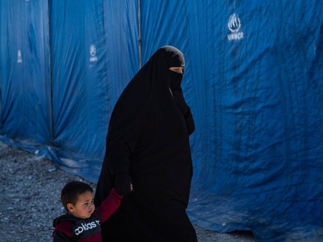 A woman leads her child during the release of another group of Syrian families from the Kurdish-run al-Hol camp which holds suspected relatives of Islamic State (IS) group fighters, in Hasakeh governorate of northeastern Syria, on February 20, 2021. (Photo by Delil SOULEIMAN / AFP) (Photo by DELIL SOULEIMAN/AFP via …