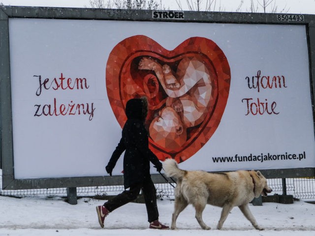 KRAKOW, POLAND - FEBRUARY 16: A woman and her dog walk past a Giant pro-life and anti-abortion banners by Kornice foundation that reads "I dependent on you" on February 16, 2021 in Krakow, Poland. On January 27, 2021 Poland’s Constitutional Court ruling from the previous months determined that abortions are …