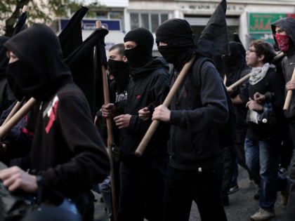 Masked protesters hold black flags as they march in Athens on December 6, 2014, during a protest to commemorate the six-year anniversary of the fatal shooting of teenager Alexis Grigoropoulos by a police officer, an event that plunged Greece into weeks of youth riots. The commemoration is held as a …