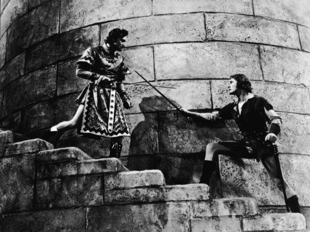 Actors Errol Flynn (R) (1909 - 1959) and Basil Rathbone (1892 - 1967) duel on a castle stairwell in a still from the film, 'The Adventures of Robin Hood,' directed by Michael Curtiz and William Keighley, 1938. (Photo by Warner Bros./Courtesy of Getty Images)
