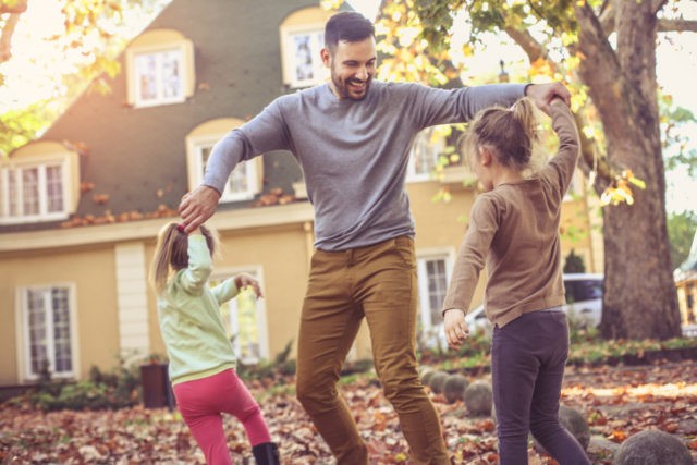 Father playing with daughter at backyard.