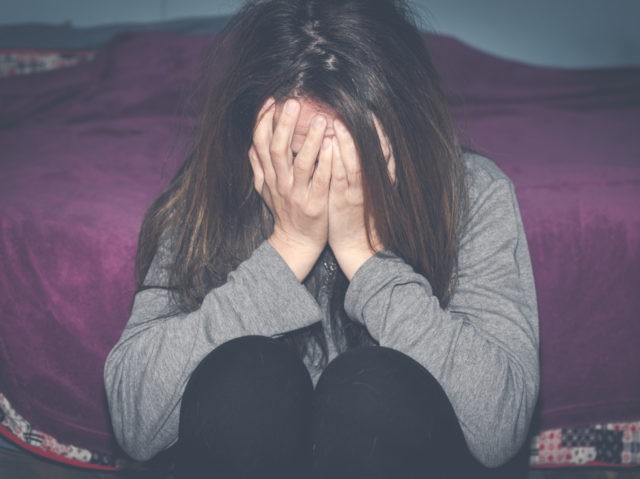 Depressed and lonely girl abused as young sitting alone in her room feeling miserable and anxiety cry over her life, dark image