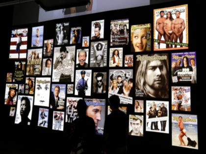 This Tuesday, Aug. 29, 2017 photo shows people looking covers of the Rolling Stone magazines at the "Rolling Stone 50 Years" exhibit at the Rock and Roll Hall of Fame, in Cleveland. (AP Photo/Tony Dejak)