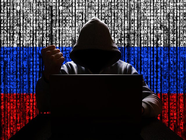 Russian hacker in the hood threatens with his fist against the backdrop of a tricolor from a binary code, cyber threat