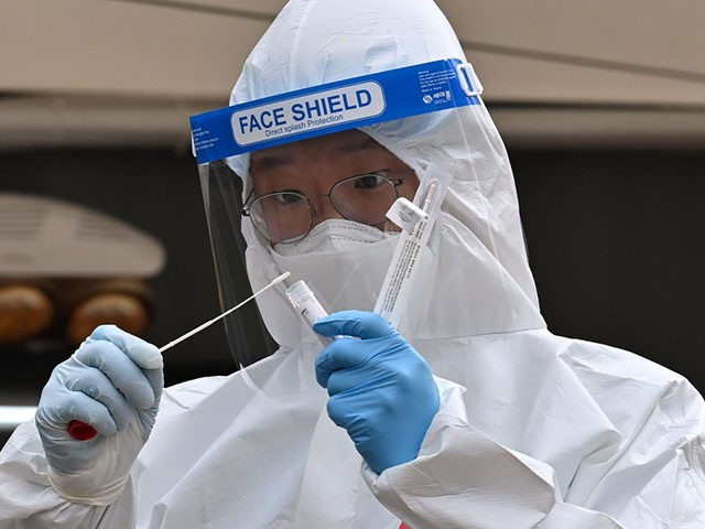 A medical staff member wearing protective gear takes a swab from a visitor to test for the Covid-19 coronavirus at a temporary testing station outside the City Hall in Seoul on December 28, 2020. (Photo by Jung Yeon-je / AFP) (Photo by JUNG YEON-JE/AFP via Getty Images)