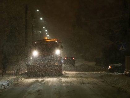 A snowplow cleaning streets in the aggravated traffic due to strong snowfall.