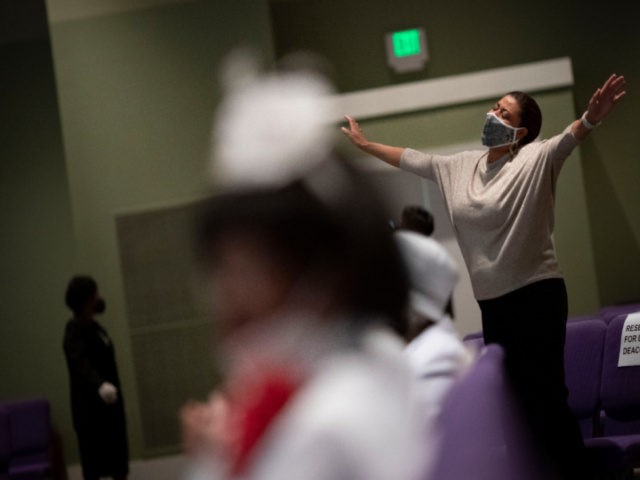 A woman wearing a face mask prays during a church service at the New Horizon International