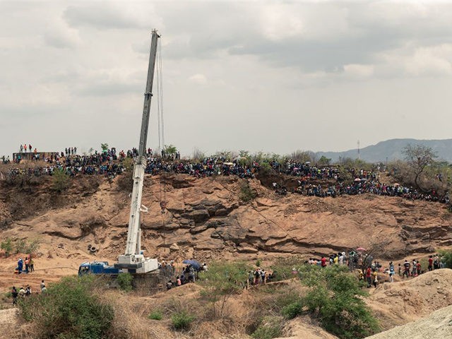Curious onlookers sitting on a hill watch closely as rescue workers busy at work installing a water pump to drain water from a mine shaft so that they can gain access to at least 40 informal gold miners trapped inside a collapsed shaft at Ran Mine in Bindura, on November …