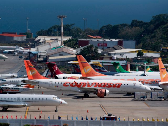 Commercial planes of different airlines and private jets sit on the tarmac at Simon Boliva