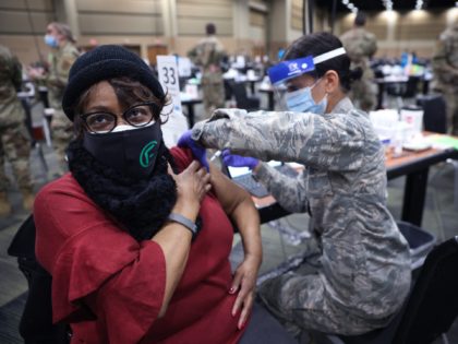 TINLEY PARK, ILLINOIS - JANUARY 26: SrA Serena Nicholas of the Illinois Air National Guard administers a COVID-19 vaccine to Larcetta Linear at a mass vaccination center established at the Tinley Park Convention Center on January 26, 2021 in Tinley Park, Illinois. The site is the first large-scale vaccination center …