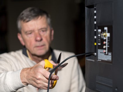 Senior man cutting the cord on his cable TV package - stock photo Close up of senior caucasian retired man cutting the aerial connection to his TV to illustrate cutting the cord