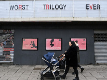 A woman wheels a pram past a shuttered cinema in Islington, north London on January 28, 2021, during the country's second national lockdown due to the novel coronavirus COVID-19 crisis. - Britain on January 26, 2021, became the first European country to pass 100,000 Covid-19 deaths, and is banking on …