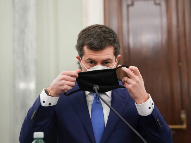 Pete Buttigieg, nominee for US Transportation Secretary, puts on his mask at his confirmation hearing before the Senate Commerce, Science, and Transportation committee in Washington, DC, on January 21, 2021. (Photo by Stefani Reynolds / POOL / AFP) (Photo by STEFANI REYNOLDS/POOL/AFP via Getty Images)