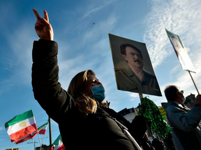 People wave former flags of Iran and hold portraits as they protest outside the Antwerp co
