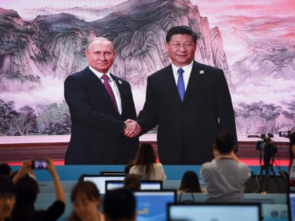A large video screen shows Chinese President Xi Jinping shaking hands with Russia's President Vladimir Putin before a meeting with head of state members of the Shanghai Cooperation Organisation (SCO) at the SCO Summit in Qingdao, China's Shandong province, on June 10, 2018. (Photo by WANG ZHAO / AFP) (Photo …