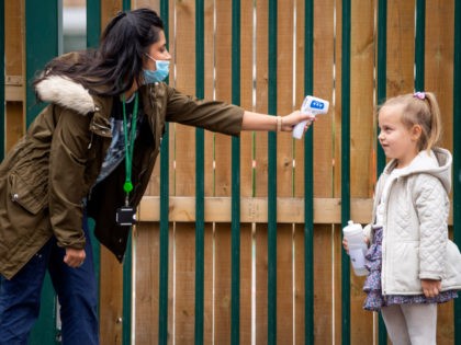 LONDON, ENGLAND - JUNE 10: A child has her temperature checked by a teacher before entering Earlham Primary School, which is part of the Eko Trust on June 10, 2020 in London, England. As part of Covid-19 lockdown measures, Earlham Primary School is teaching smaller ‘bubbles’ of students, to help …