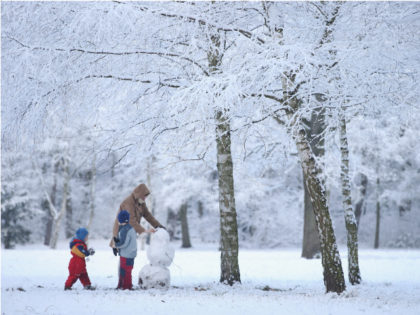BERLIN, GERMANY - DECEMBER 26: A mother and two children build a snowman in a snow-covered park in Zehlendorf district during the season's first snowfall on December 26, 2014 in Berlin, Germany. Germany has so far experienced a very mild winter. (Photo by Sean Gallup/Getty Images)