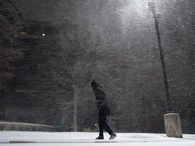 A woman walks through falling snow in San Antonio, Sunday, Feb. 14, 2021. Snow and ice bla