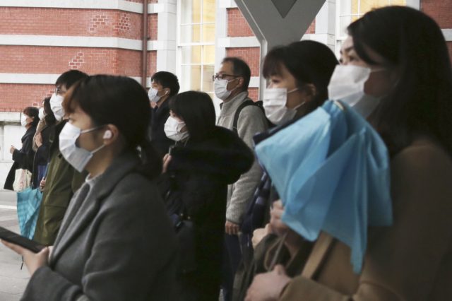 People wearing face masks to protect against the spread of the coronavirus wait for signals to turn to green at a crossing in Tokyo, Monday, Feb. 15, 2021. Tokyo is under state of emergency as the government seeks to stop a surge of new coronavirus infections. (AP Photo/Koji Sasahara)
