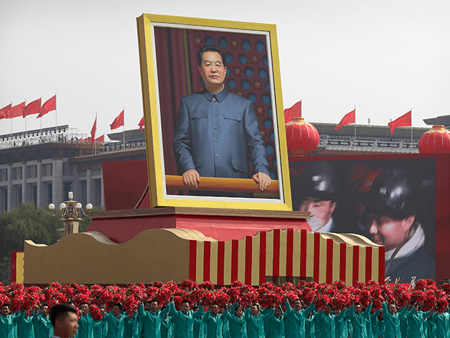 Participants wave floral bouquets as they march next to a large portrait of Chinese leader