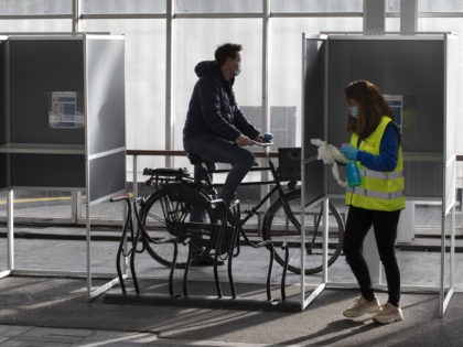 An election official disinfects voting booths in a ride through polling station for bicycles in Amsterdam, Netherlands, Monday, March 15, 2021. Polling stations opened across the Netherlands early Monday in a general election that has been spread over three days to allow people to vote safely during the coronavirus pandemic. …