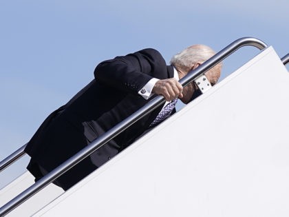 President Joe Biden holds onto a railing after stumbling while boarding Air Force One at Andrews Air Force Base, Md., Friday, March 19, 2021. Biden is en route to Georgia. (AP Photo/Patrick Semansky)