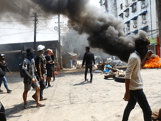 Anti-coup protesters gather around their makeshift barricade they burn to make defense line during a demonstration in Yangon, Myanmar, Sunday, March 28, 2021. Protesters in Myanmar returned to the streets Sunday to press their demands for a return to democracy, just a day after security forces killed more than 100 …
